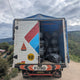 Truck with open cargo area on a dirt road under a cloudy sky