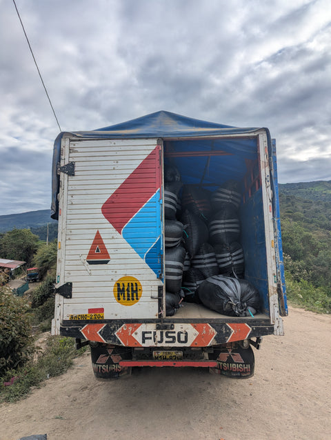 Truck with open cargo area on a dirt road under a cloudy sky